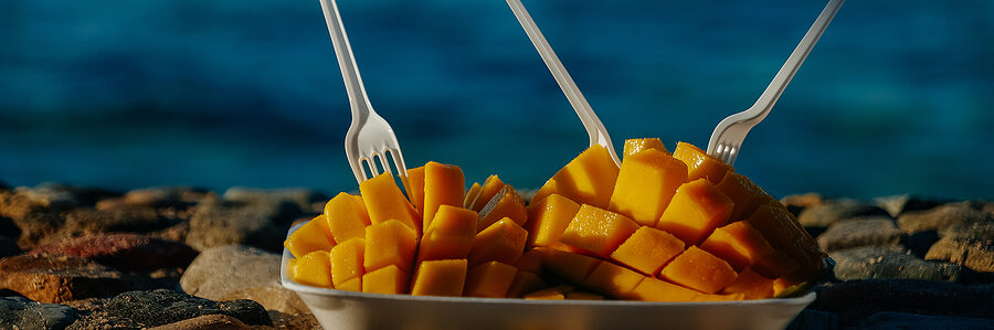 a tray of mangoes with plastic forks