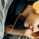 a child sleeping in bed with headphones on