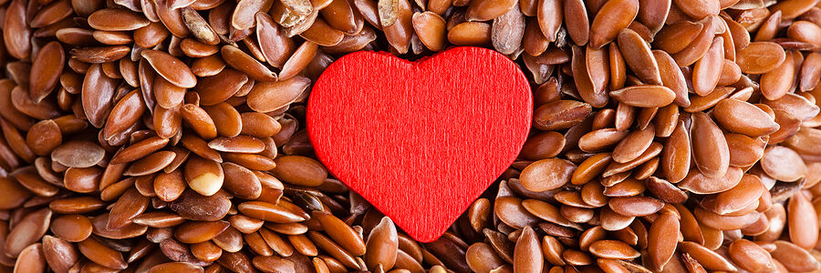 a heart shaped object on top of brown flax seeds